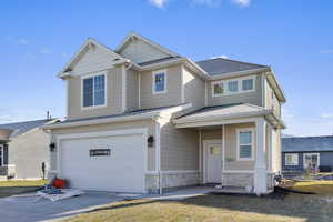 Craftsman-style house featuring an attached garage, roof with shingles, stone siding, and driveway