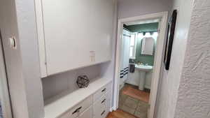 Bathroom with a textured wall and a shower with curtain