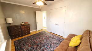 Bedroom with crown molding, light wood finished floors, and a ceiling fan