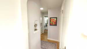 Hallway with light wood-type flooring and baseboards