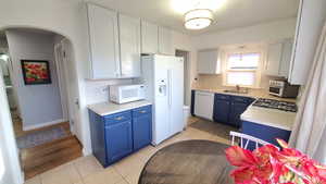 Kitchen with blue cabinets, light countertops, and light tile floors