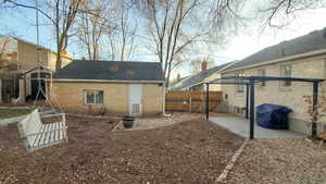 Rear view of property featuring brick siding, a fenced backyard, roof with shingles, and a patio