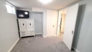 Carpeted bedroom featuring a textured ceiling and baseboards