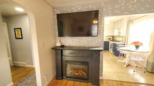 Living room with arched walkways, light wood-type flooring, and a glass covered fireplace