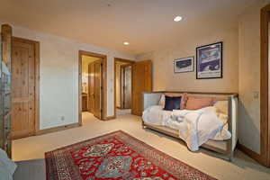 Bedroom with recessed lighting, light colored carpet, and ensuite bathroom
