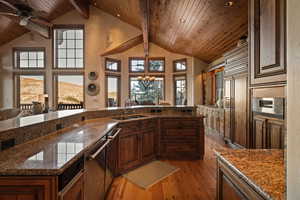 Kitchen featuring light wood-type flooring, dark stone counters, a chandelier, a high wood beamed ceiling, and ceiling fan