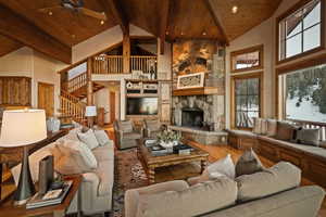 Living room with hardwood / wood-style flooring, a fireplace, ceiling fan, and a high wood beamed ceiling