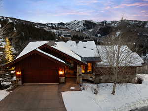 Rustic home with a mountain view, an attached garage, board and batten siding, concrete driveway, and stone siding