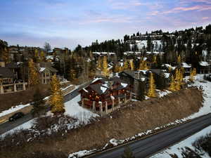 Snowy aerial view featuring a residential view and view of wooded area