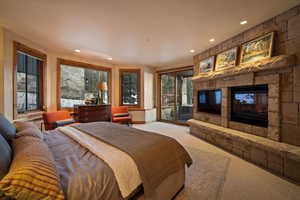 Carpeted bedroom with a stone fireplace, access to outside, and recessed lighting