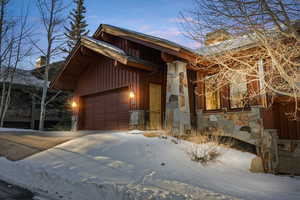View of front of house with stone siding, a chimney, board and batten siding, and a garage