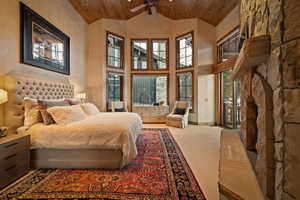 Bedroom with wood ceiling, a stone fireplace, carpet floors, and high vaulted ceiling