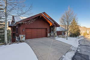 Rustic home featuring stone siding, concrete driveway, and an attached garage