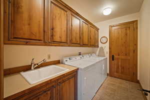 Laundry room featuring cabinet space, washer and dryer, a textured ceiling, and light tile patterned floors
