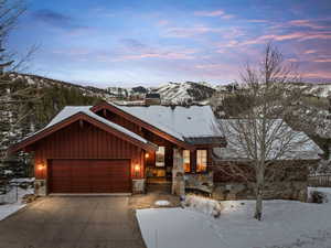 Rustic home featuring a chimney, stone siding, a mountain view, driveway, and board and batten siding