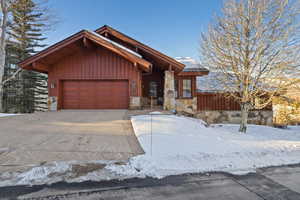 View of front facade with stone siding, a garage, concrete driveway, and board and batten siding