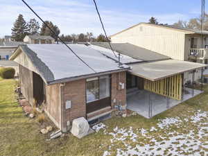 Rear view of property featuring roof with shingles, brick siding, a patio, and a lawn
