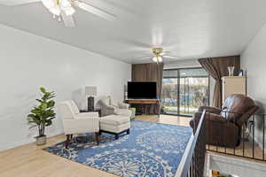 Living area with light wood-type flooring and a ceiling fan