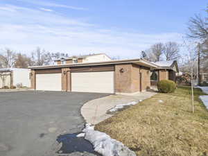 View of front of property featuring asphalt driveway, a front lawn, and brick siding