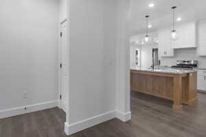 Kitchen featuring white cabinetry, light stone counters, recessed lighting, decorative backsplash, and stainless steel range