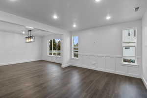 Empty room with a decorative wall, wainscoting, dark wood finished floors, and recessed lighting