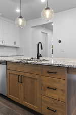 Kitchen with light stone countertops, brown cabinets, and decorative light fixtures