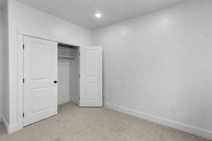 Unfurnished bedroom featuring light carpet, a closet, and recessed lighting