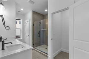 Bathroom with a shower stall, double vanity, and recessed lighting