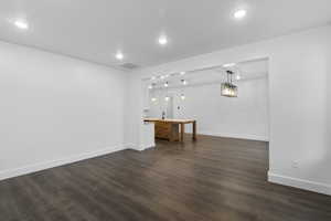 Unfurnished living room featuring dark wood-style flooring and recessed lighting