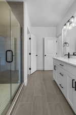 Full bath with double vanity, a stall shower, and light tile patterned floors