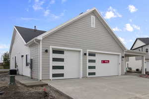 View of property exterior with concrete driveway and a garage