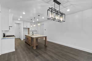 Kitchen featuring white cabinets, brown cabinetry, light stone counters, decorative light fixtures, and recessed lighting