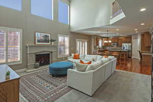 Living room with a glass covered fireplace, recessed lighting, a chandelier, a towering ceiling, and dark colored carpet
