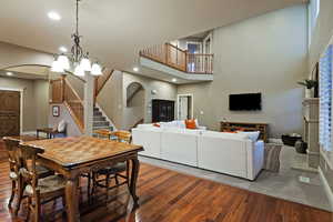 Dining room featuring stairs, hardwood / wood-style floors, a chandelier, a towering ceiling, and recessed lighting