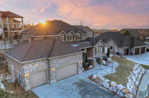 View of front of house featuring concrete driveway, an attached garage, stone siding, and a shingled roof