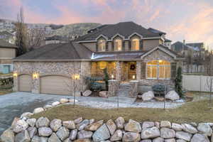 View of front of house with covered porch, stone siding, driveway, an attached garage, and stucco siding