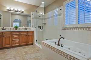Bathroom with a whirlpool tub, double vanity, a stall shower, and light tile patterned flooring