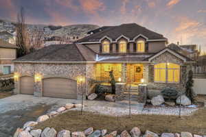 View of front of home featuring stone siding, covered porch, driveway, and an attached garage