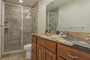 Bathroom featuring vanity, a stall shower, and stone tile floors