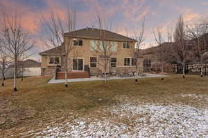 Back of house featuring a patio area, stucco siding, and stone siding