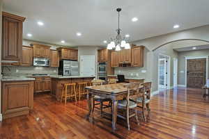 Kitchen featuring brown cabinetry, a center island, arched walkways, hanging light fixtures, and recessed lighting
