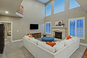 Carpeted living area featuring a premium fireplace and a high ceiling