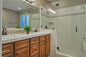 Full bath featuring double vanity, a shower stall, and recessed lighting