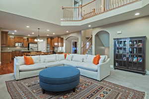 Living area with recessed lighting, stairs, arched walkways, a towering ceiling, and carpet