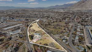 Aerial view of property and surrounding area featuring a mountainous background and nearby suburban area