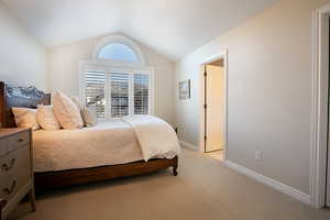 Bedroom featuring light colored carpet and vaulted ceiling