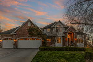 Brick, Hardie Board Exterior with sidewalk lined with boxwoods and ivy growing over garage.