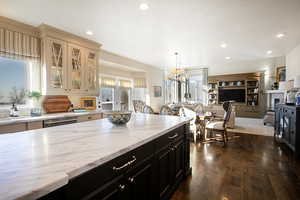 Kitchen featuring dark cabinets, light stone countertops, recessed lighting, dark wood-type flooring, and glass insert cabinets