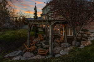 Patio terrace at dusk with a pergola, a fire pit, a patio area, and a yard