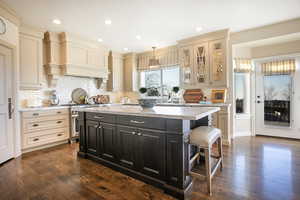 Kitchen with cream cabinets, hanging light fixtures, dark wood finished floors, dark island, and recessed lighting
